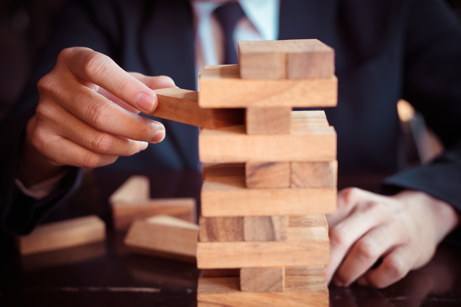 Business Man Placing Wooden Block on a Tower Concept Risk Contro